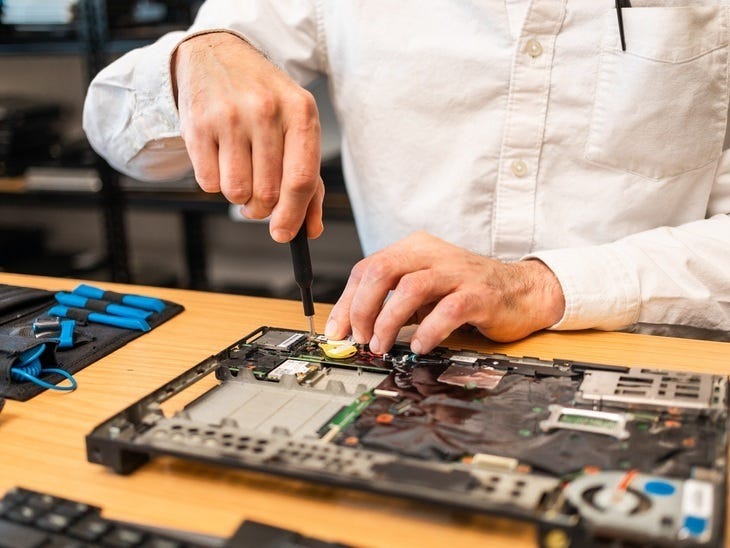 A person's hands seen repairing an electrical motherboard