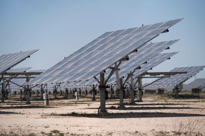 Rows of solar panels in a field at a solar farm.