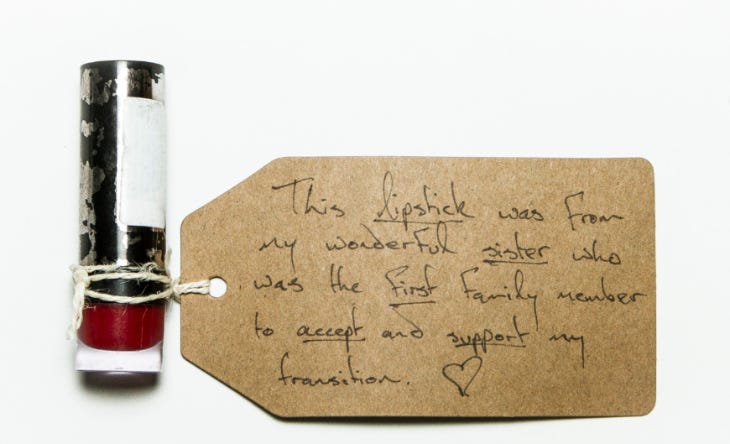 A photograph of a lipstick with a handwritten tag reading ""This lipstick was from my wonderful sister who was the first family member to accept and support my transition. ❤️"