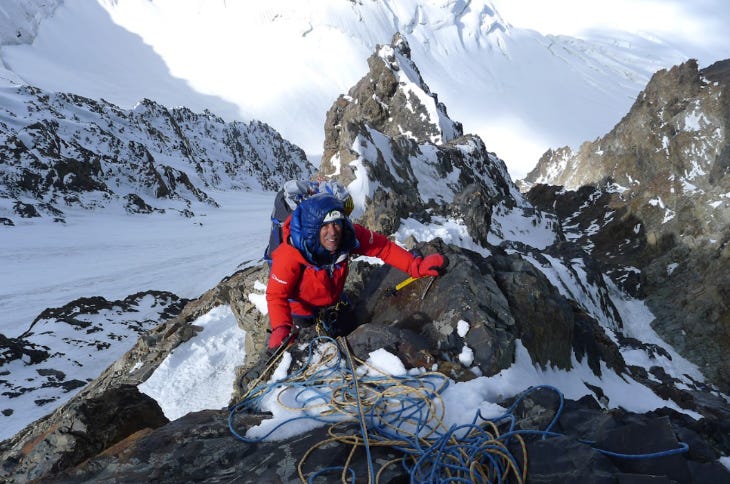 A man in a red coat climbing a mountain