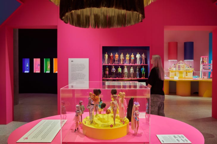 A display of Barbie dolls in a pink room in the Barbie exhibition