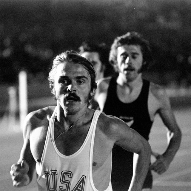 steve prefontaine wearing a usa vest and running ahead of other athletes on a track
