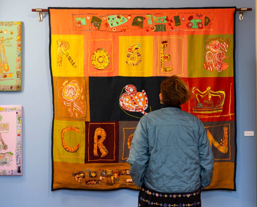 A woman looking at a textile artwork hanging on a wall