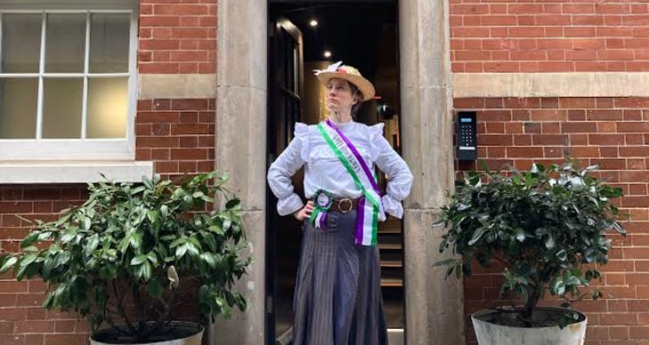 A woman dressed as a Suffragette posing at the door of the Bow Street Police Museum.