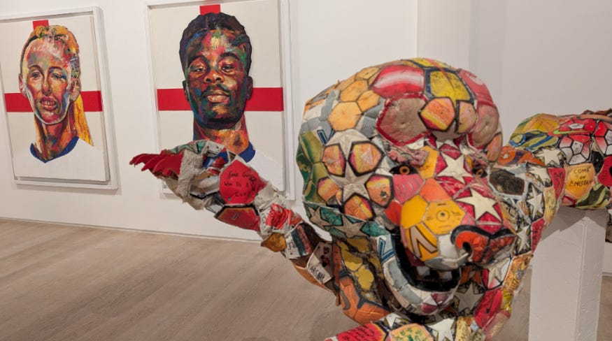 A lion sculpture in front of portraits of footballers Chloe Kelly and Bukayo Saka