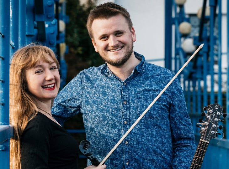 Two people holding their instruments and smiling for the camera