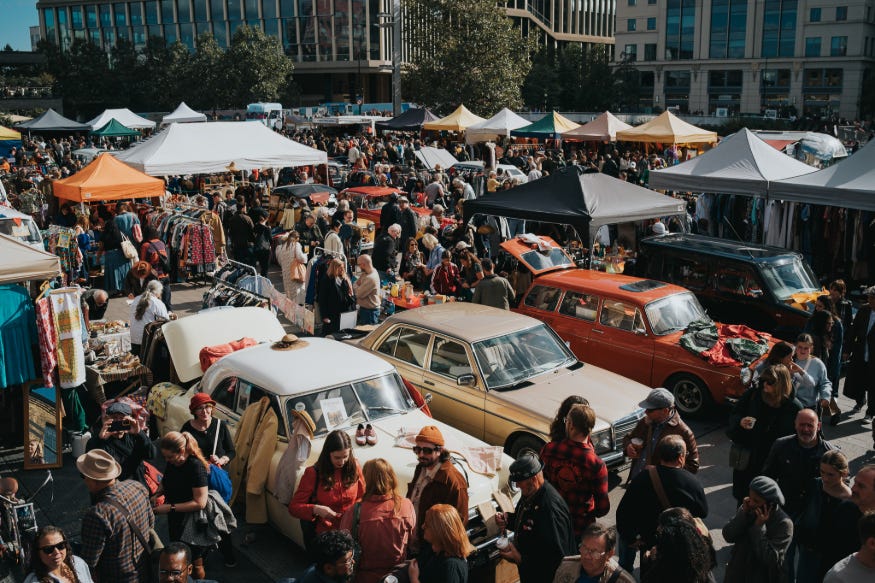 Classic cars parked in Granary Square, with people walking between them