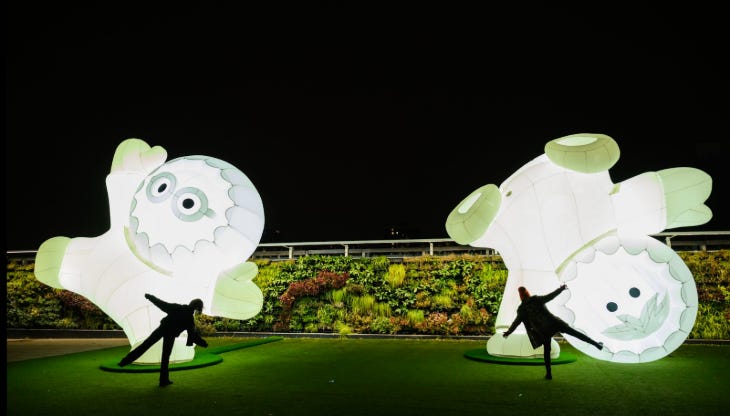Two people silhouetted in front of two white giant glowing Inuit characters