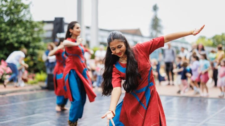 A woman in a red and blue traditional Indian style dress dancing with long dark hair 