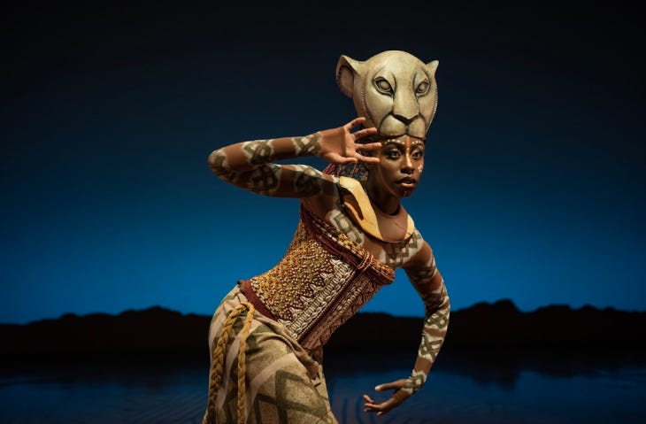 A performer in lioness costume and mask on stage in Disney's The Lion King