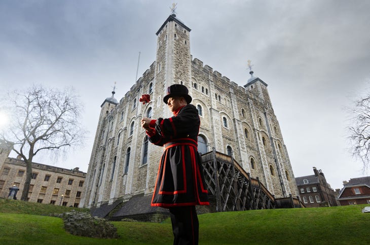 A yeoman warder holds a red rose