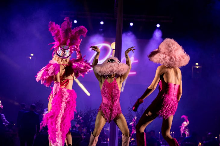 Three performers dressed as flamingos dancing