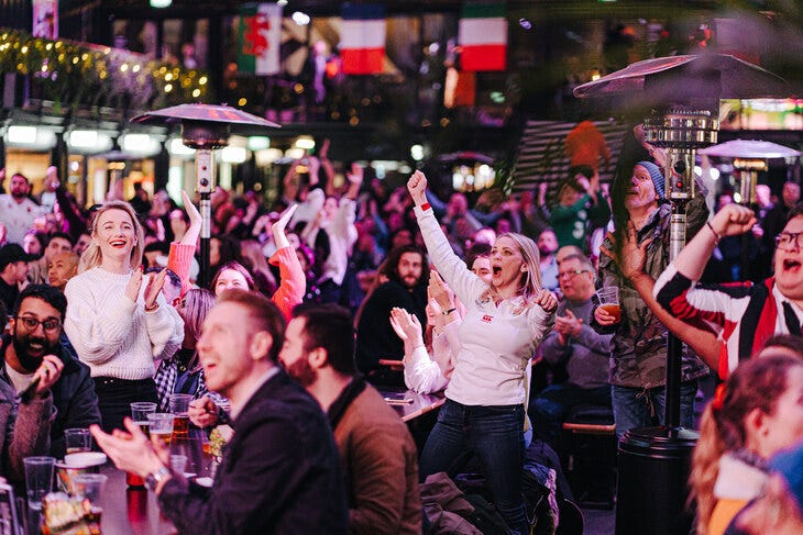 People clapping and cheering at a screening of a rugby match