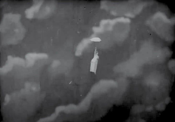 Old film of a woman floating through the skies with an umbrella
