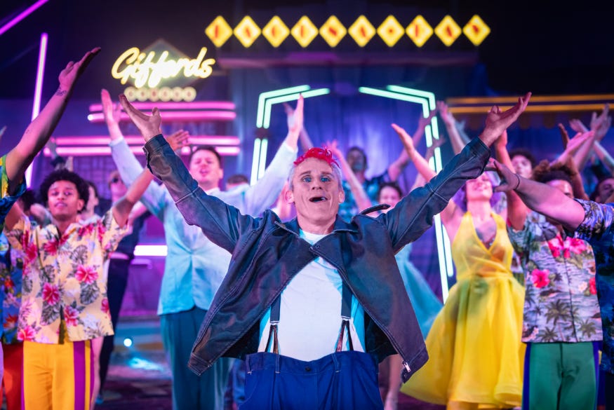 Performers on stage at Gifford's Circus with their arms lifted towards the sky
