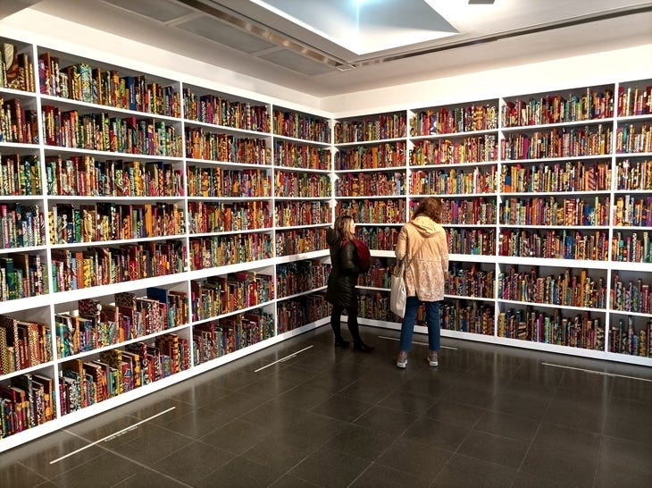 People admiring a colourful bookshelf artwork