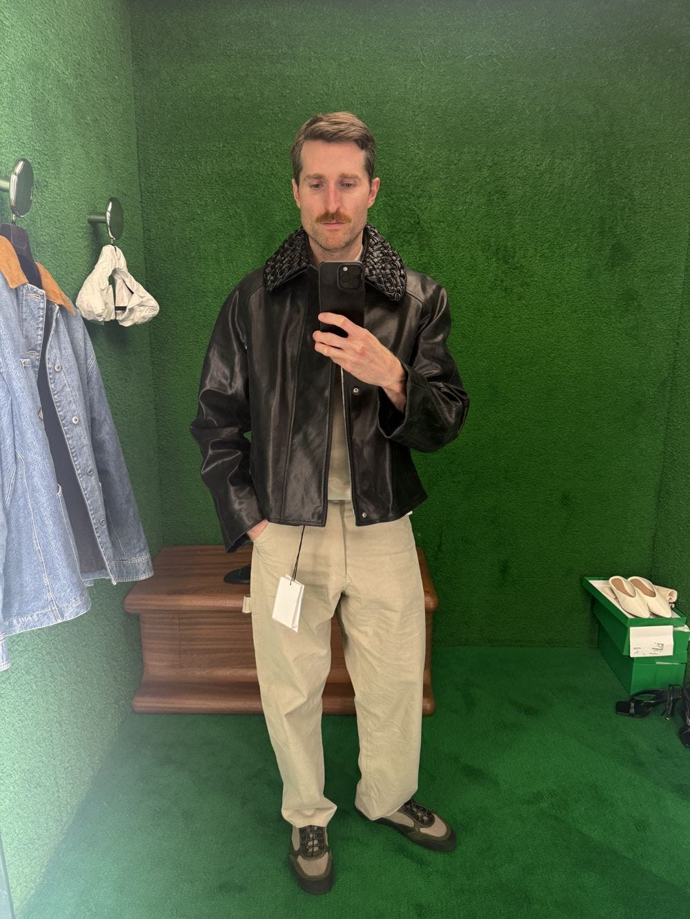 Brian trying on a Bottega Veneta leather jacket in the fitting room