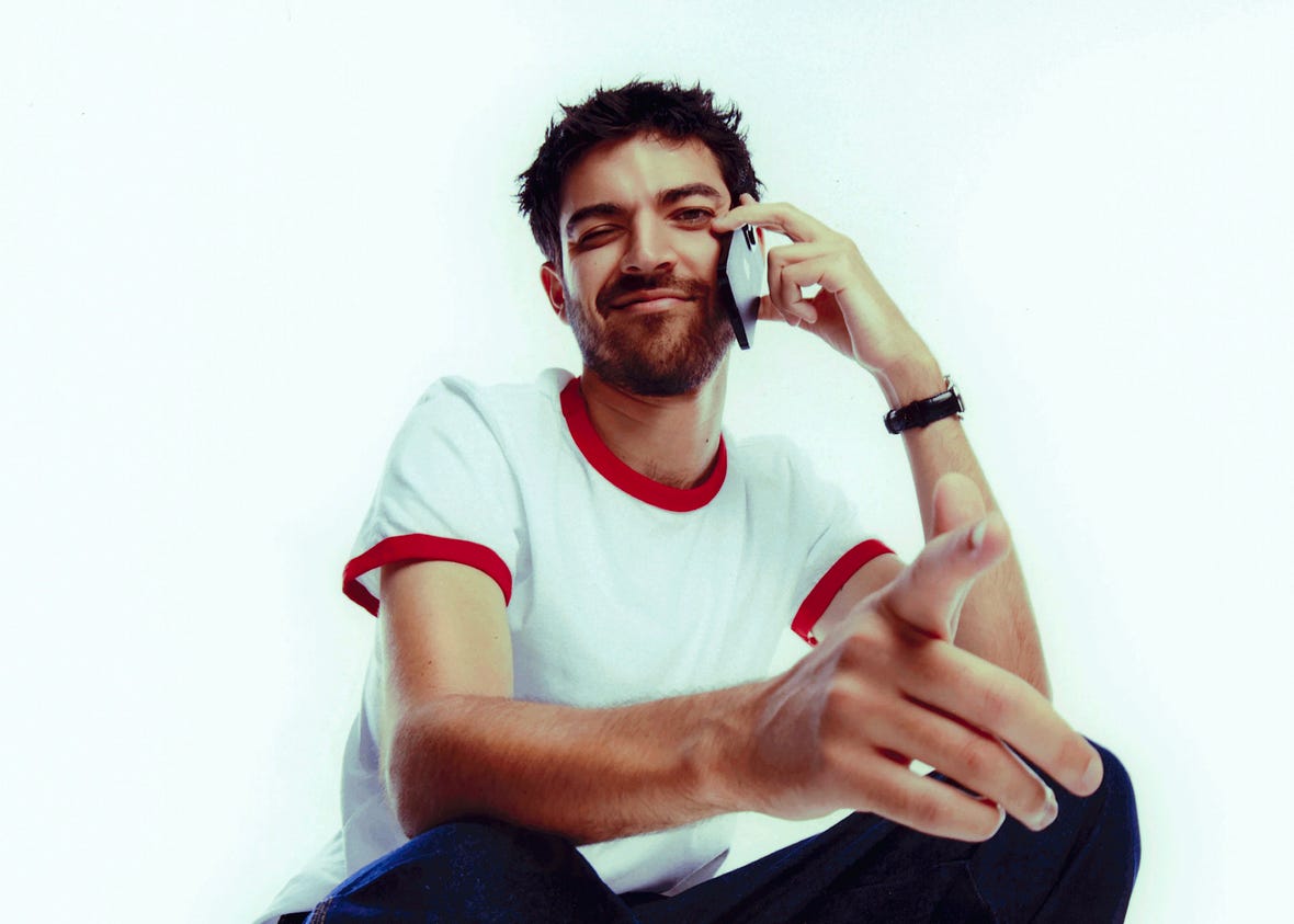 Portrait of Adam Faze, producer and studio chief of FazeWorld, holding an iphone to his ear.