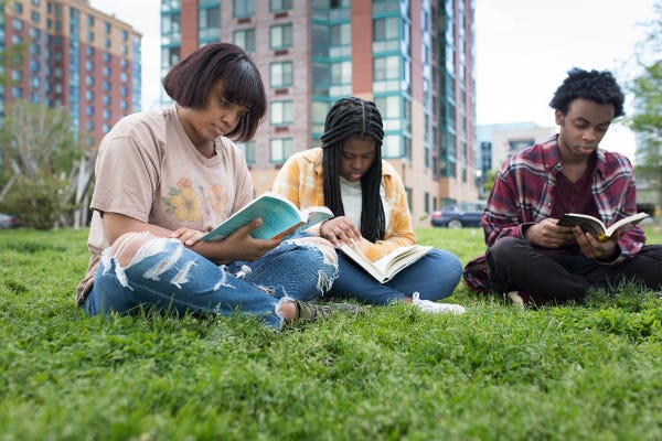 Three friends are reading in a park. Image courtesy of @childrennaturenetwork.