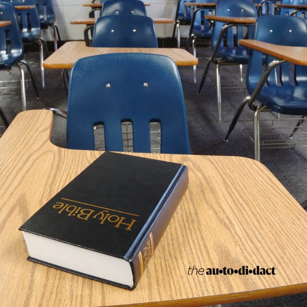 A Bible sits on a school desk.