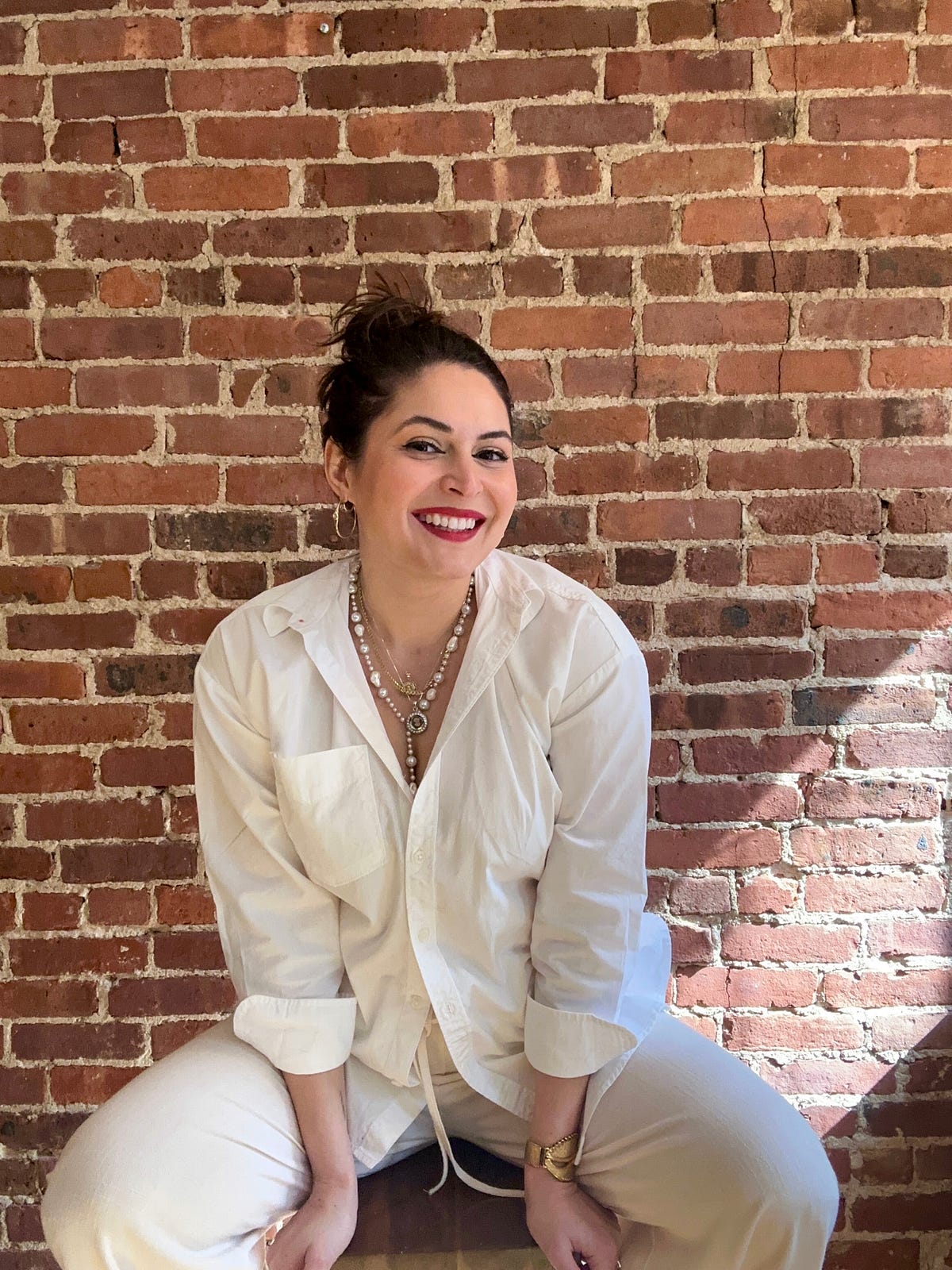Itzett Romero in a white shirt in front of a brick wall