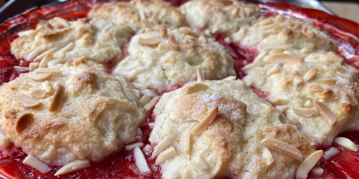 Strawberry cobblers topped with slivered almonds in a clear pie plate.
