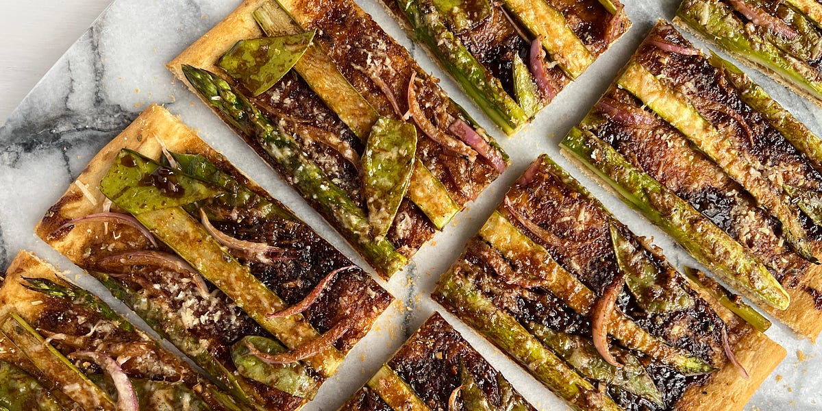 Vegetable tart with asparagus, snow peas and red onion on a marble countertop. 