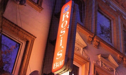 A red lit-up sign reading Rosi's Bar, complete with idiot's apostrophe