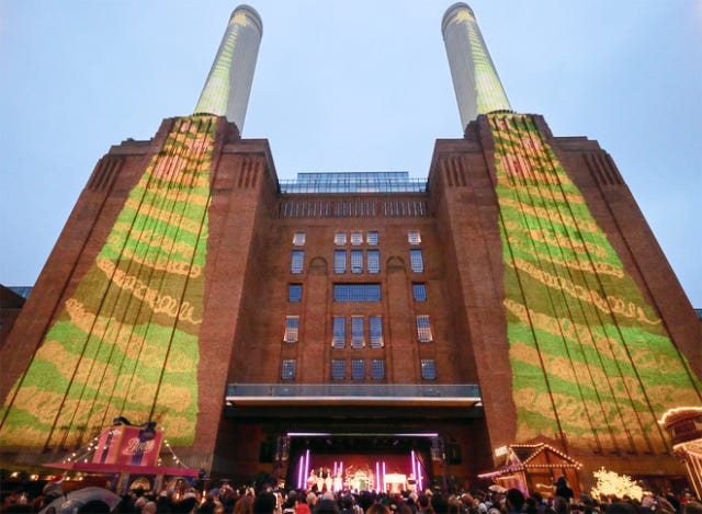 Christmas tree artwork created on iPad by the students at St. George’s Primary School is projected onto the power station’s iconic chimneys as British musician RAYE performs a festive set for the local community.