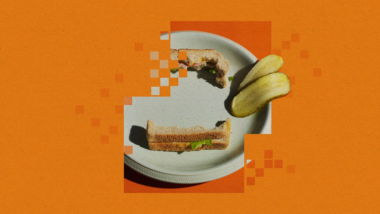 a pixelated plate with the crusts of a sandwich and two pickle slices