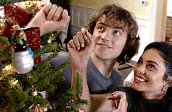 gif of Sir Cole and Vanessa Hudgens in The Knight Before Christmas putting an ornament on a Christmas tree.