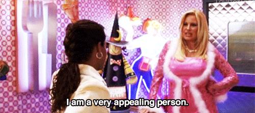 Gif of Jennifer Coolidge in "A Cinderella Story" dressed in pink dress with white faux fur lining. Captioned: "I am a very appealing person." Regina King looks at her unimpressed.