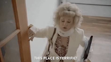 GIF: Amy Sedaris, wearing a neck brace, says, "This place is terrific! It's a prewar building built right after the Iraq War."