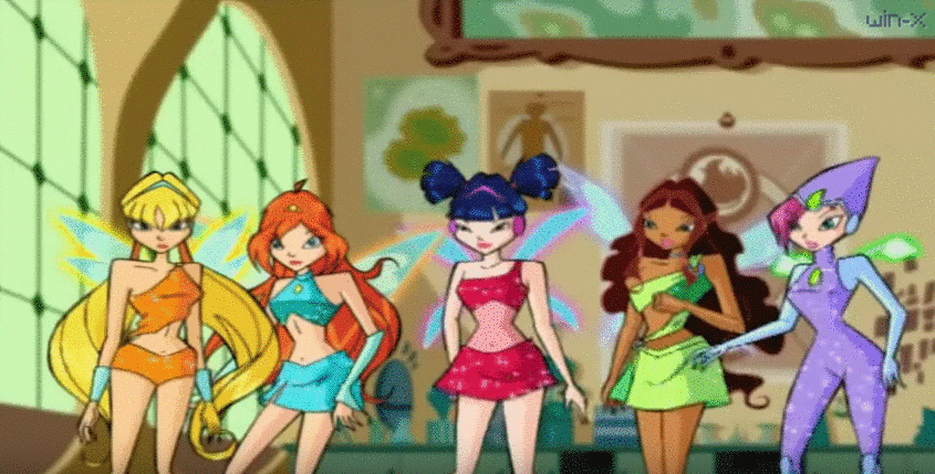 the winx club girls are in their fairy transformation outfits in Alfea. they break out in celebration. on the left, stella hugs bloom. musa, layla and tecna high-five each other to the right.