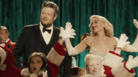 Gwen Stefani shimmers and shines in a Christmas special, while Blake Shelton bobbles next to her with a confused expression on his face.