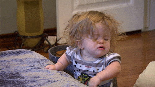 Imagem de um nenê cansado que deita meio chorando na cama