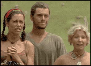 Classic “Survivor” gif where two women cover their moths in shock and horror and then the guy standing behind them grins horribly.