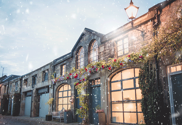 The Nile office - a small mews building in Edinburgh - illuminated with warm light in ananimated snowshower
