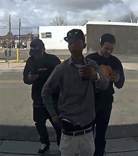 gif of three men standing in front of a camera and holding their phones, the one in the middle brandishing a gun