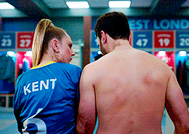Keeley and Roy seen from behind as Keeley (wearing a Kent jersey) hugs Roy (shirtless) to her