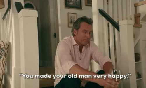 John Corbett in 'To All the Boys I've Loved Before' sitting on the stairs with a glass of white wine in a pink shirt with the sleeves rolled up. John Corbett in 'To All the Boys I've Loved Before' sitting on the stairs with a glass of white wine in a pink shirt with the sleeves rolled up.