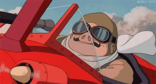 Gif da Porco Rosso di Hayao Miyazaki. Un maiale antropomorfo vestito da aviatore fa segno col pollice in su e sorride mentre è al volante del suo biplano rosso, in volo in cielo.