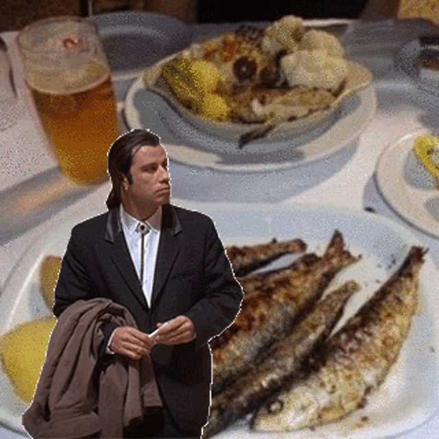 a man in a suit is standing next to a plate of fish and a glass of beer