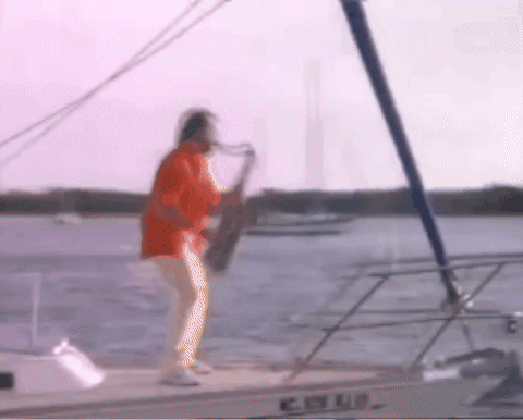 GIF of Lee Greenwood playing a sax on a sailboat