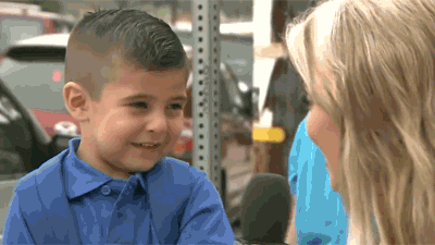 Gif de mulher entrevistando uma criança que, no momento de responder a pergunta, tenta disfarçar o choro mas não aguenta 