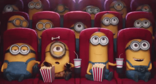 Gif dei Minion che guardano stupiti un film in un cinema, mangiando popcorn