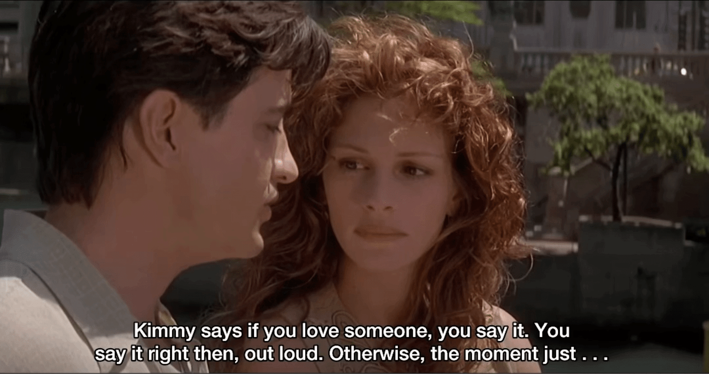 A gif from "My Best Friend's Wedding." Julianne and Michael are on a boat. Michael is talking to Julianne. Text on the image reads "Kimmy says if you love someone, you say it. You say it right then, out loud. Otherwise, the moment just . . . "