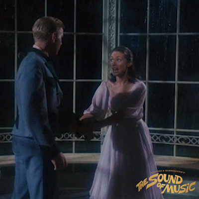 GIF of Liesl, a young girl in a poofy dress, twirling in front of Rolfe, a blonde boy in a uniform