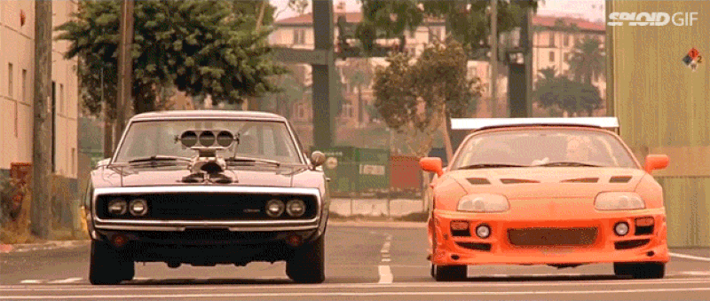 Gif di una sequenza di "Fast & Furious" con la Dodge guidatada Dominic Toretto che, al verde del semaforo, impenna mentre accanto lo sfida una macchina sportiva arancione.