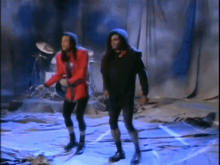 GIF of milli vanilli doing a silly dance and kicking their legs out to the side